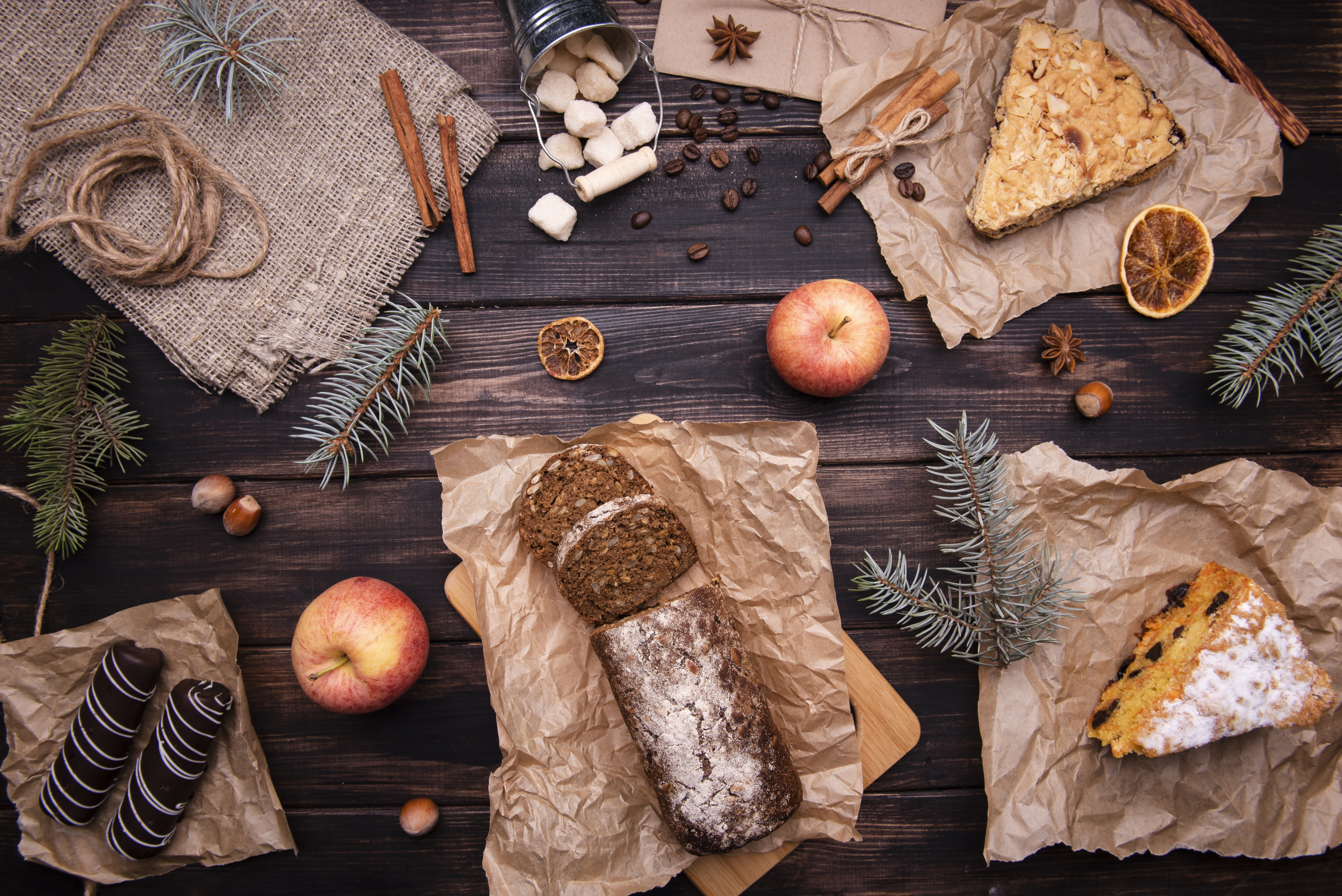 Flat-lay rustic spread with rye bread, apples, cinnamon and pine sprigs